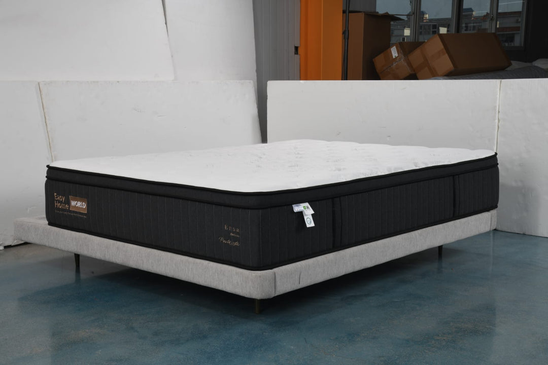 Modern foam mattress with black sides and white top on a light platform bed in showroom