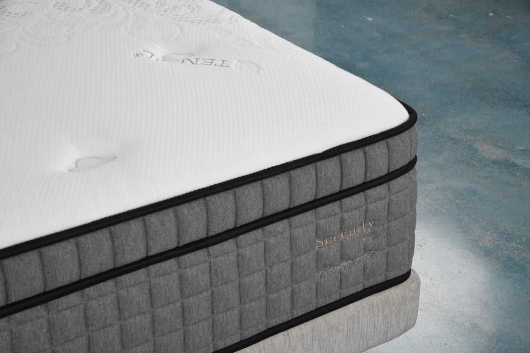 Close-up of a modern grey and white mattress with quilted sides on a platform bed