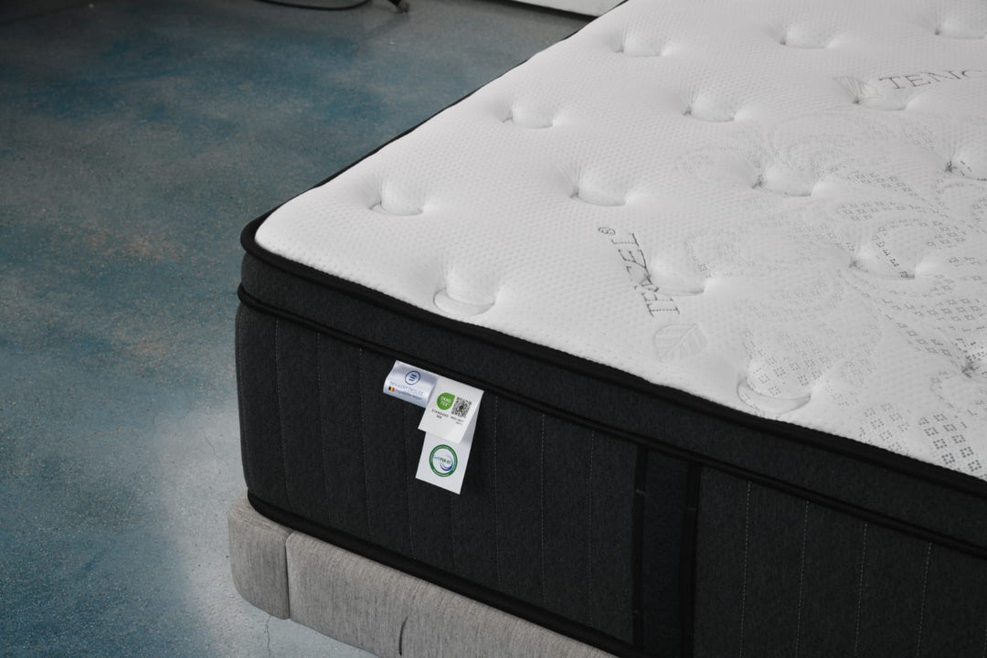 Close-up of a modern white and black mattress with Tencel fabric on a bed frame