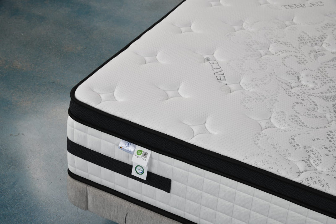 Close-up of a white Tencel fabric mattress with black trim and quilted pattern on bed base
