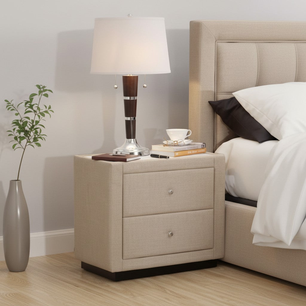 Modern beige upholstered nightstand with two drawers beside bed, lamp, and decor in bedroom
