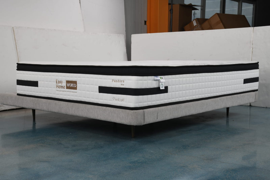 Firm white mattress with black trim on a modern upholstered bed base in a showroom
