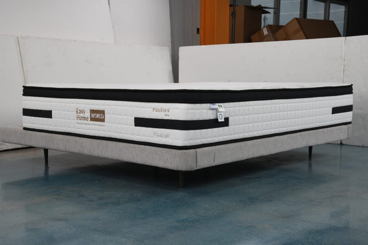 Firm white mattress with black trim on a modern upholstered bed base in a showroom