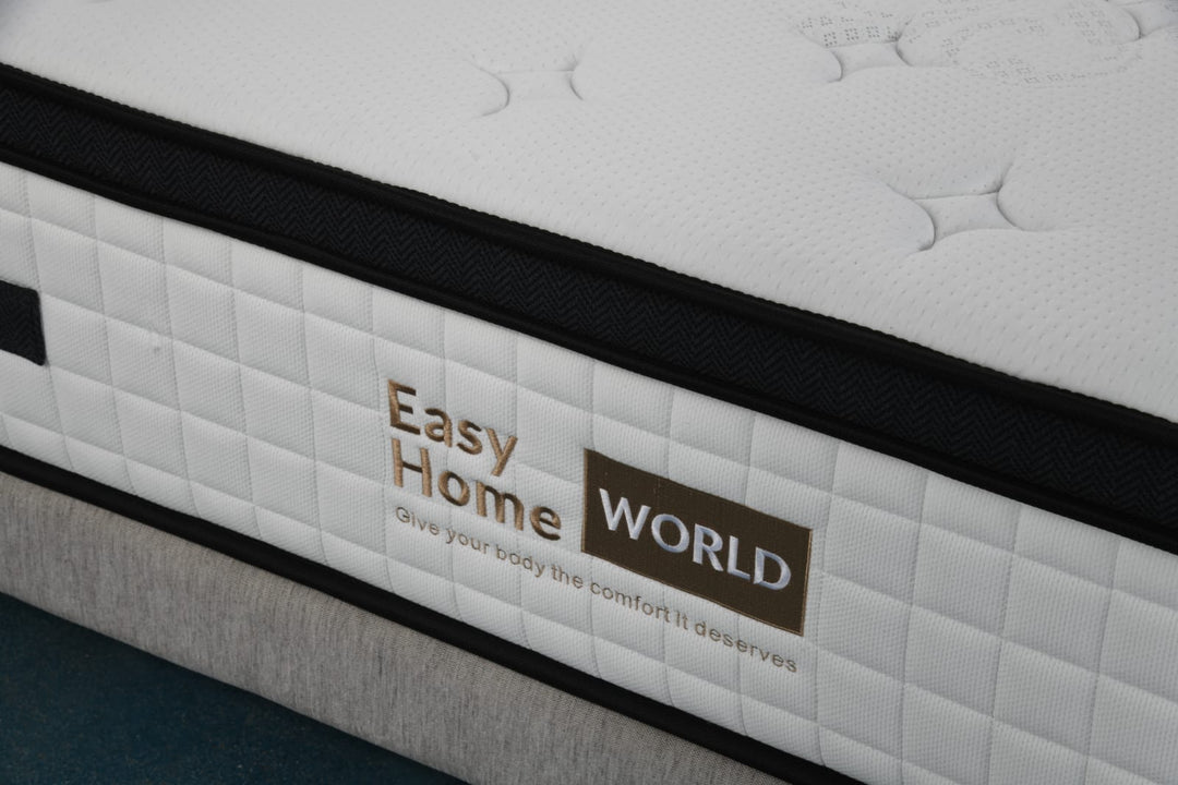 Close-up of a white quilted mattress with black trim and Easy Home World logo, on a bed base.