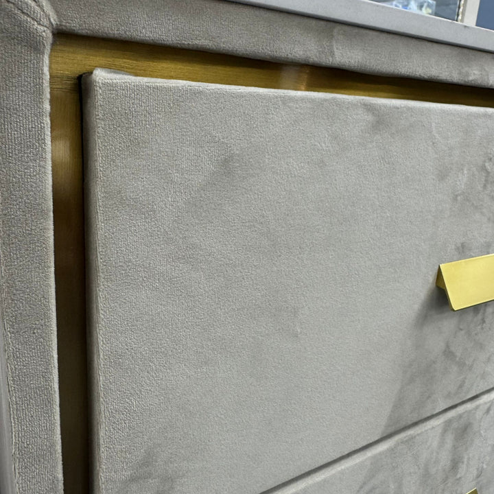 Close-up of modern gray upholstered dresser with gold drawer handle