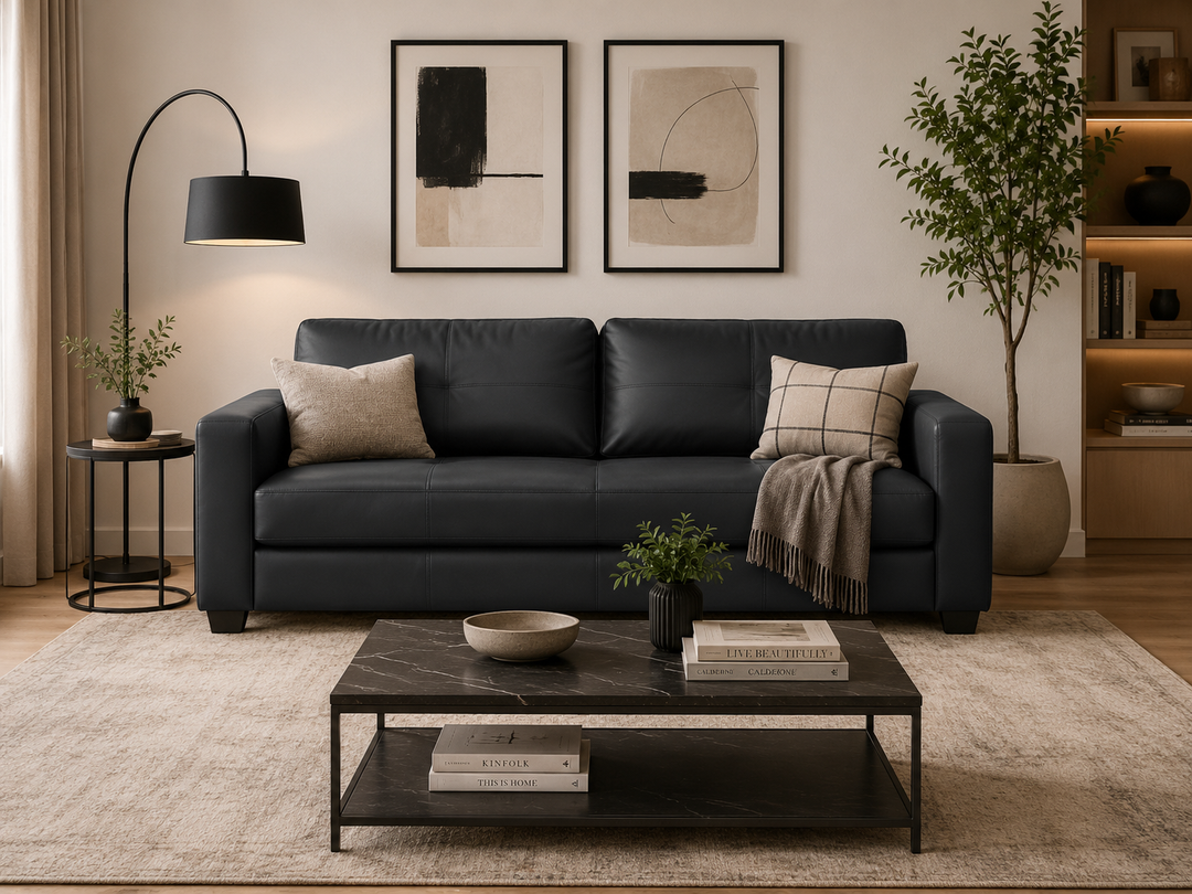 Modern black leather sofa with throw pillows and blanket in stylish living room setup