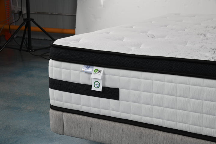 Close-up of a modern white and black mattress with quilted surface on a bed base