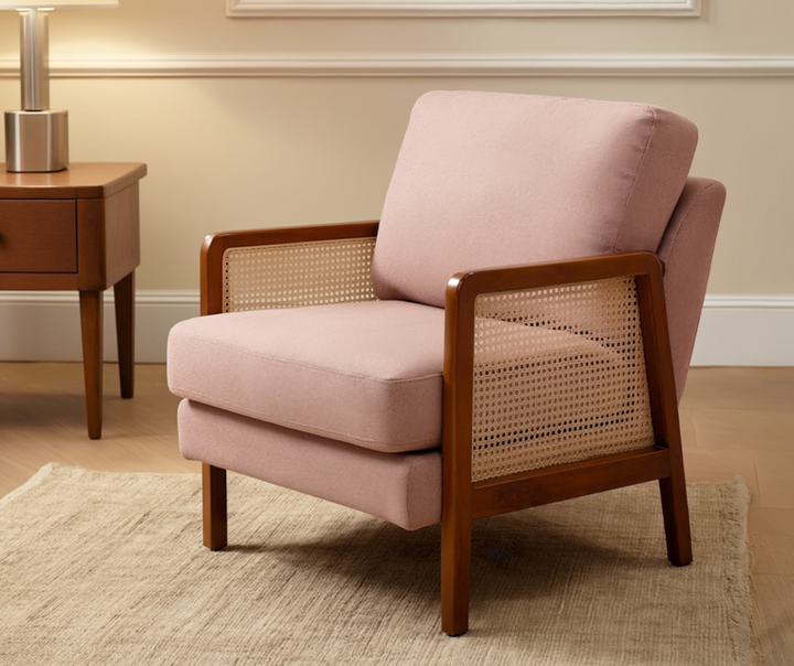 Modern accent chair with pink upholstery, wooden frame, and woven rattan sides in a living room
