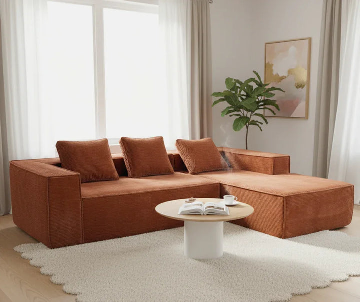 Modern living room with a brown sectional sofa, round coffee table, and large windows