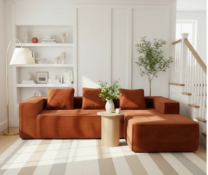 Modern rust sectional sofa with chaise in bright living room, round coffee table and indoor plant