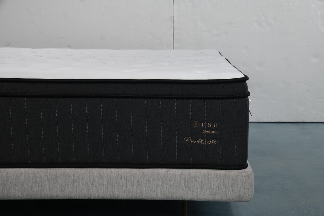 Medium firmness Ersa Posture mattress with white top and dark sides on upholstered bed base