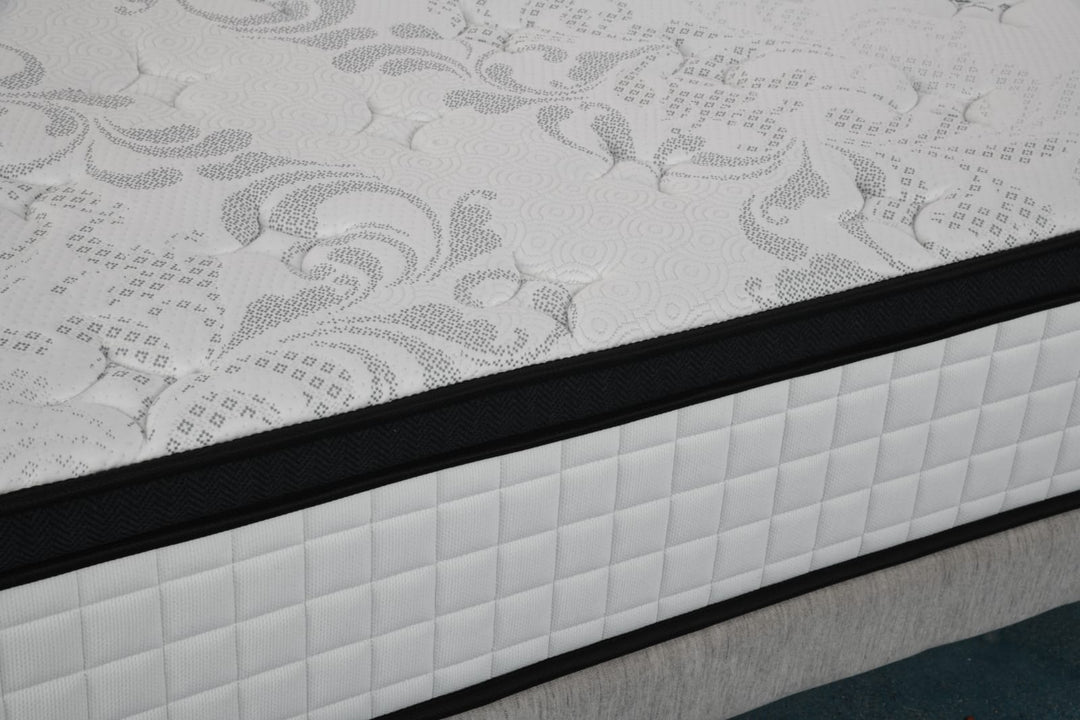 Close-up of a white patterned mattress with quilted sides on a bed base