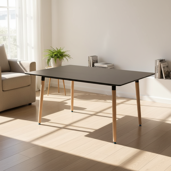 Modern dining table with black top and light wood legs in bright living room