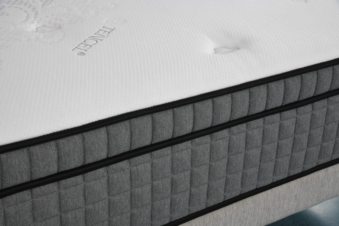 Close-up of a modern mattress with white quilted top and grey side panel upholstery