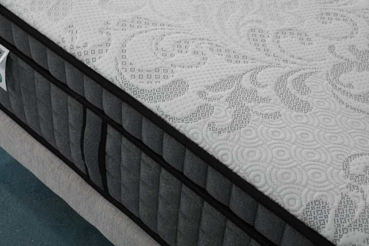 Close-up of a modern mattress with quilted white and grey pattern on a bed frame