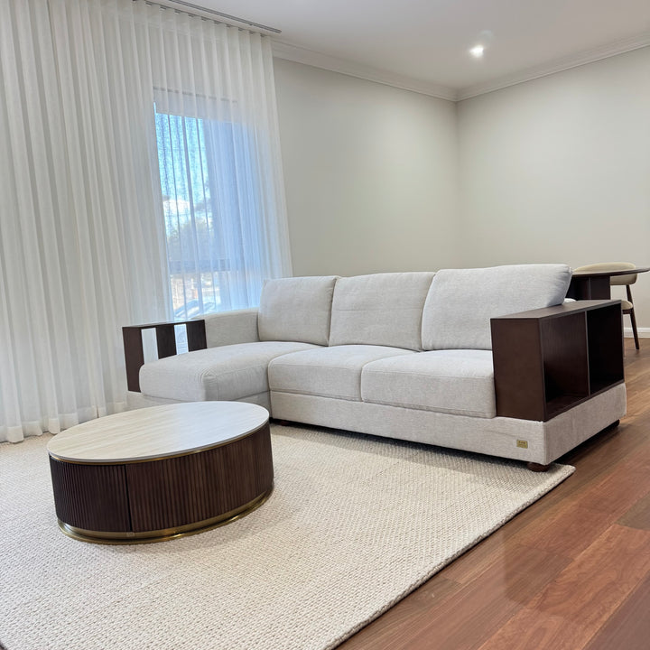 Modern beige sofa with wooden armrests and round coffee table in bright living room