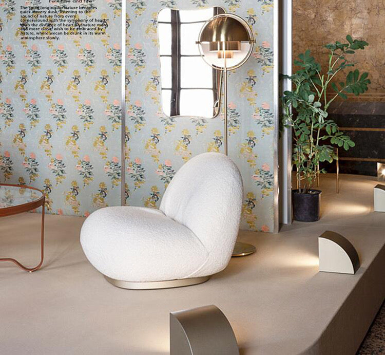 White textured armchair with gold base in modern living room with floral wallpaper and floor lamp