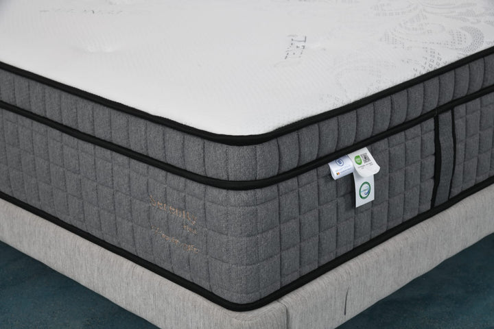 Modern grey and white mattress with quilted fabric and comfort tags on a bed base