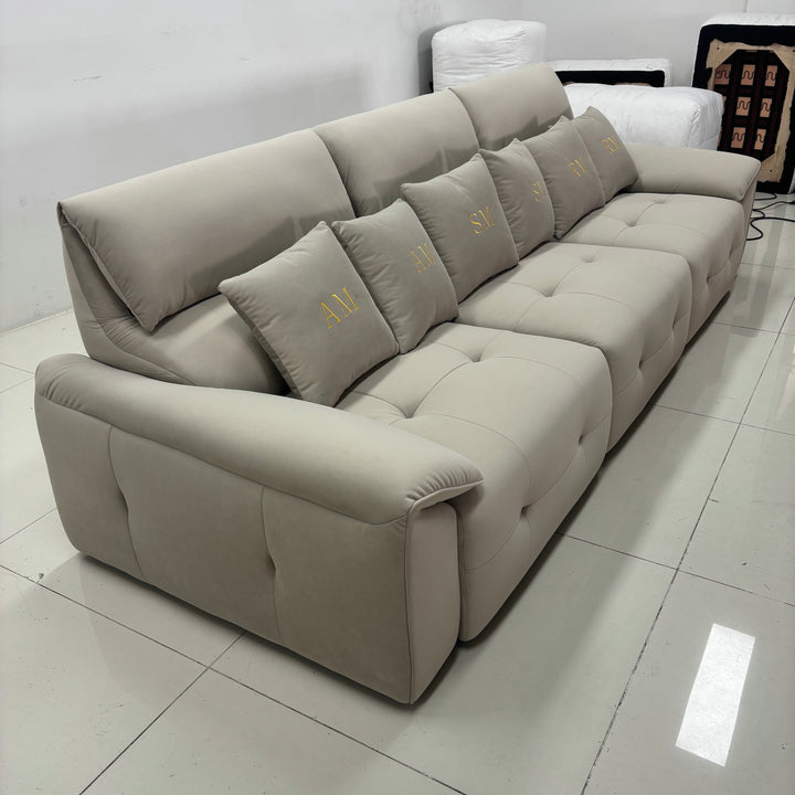 Modern beige sectional sofa with tufted cushions and embroidered accent pillows in a showroom