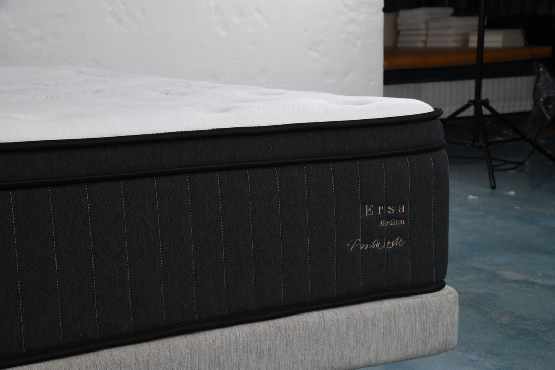 Close-up of a modern medium-firm mattress with black fabric sides and white top