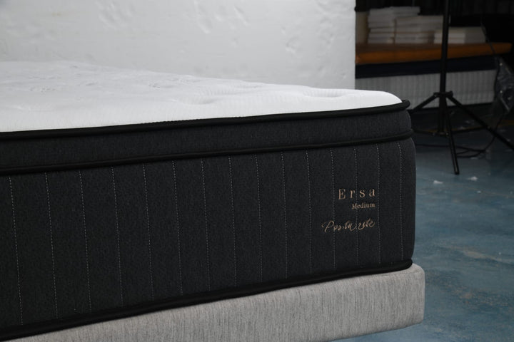 Close-up of a modern medium-firm mattress with black fabric sides and white top