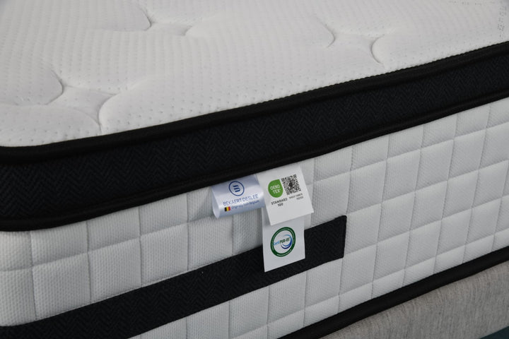 Close-up of a white quilted mattress with certifications and black trim detail