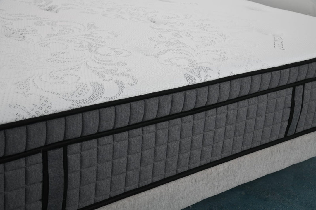 Close-up of a modern foam mattress with quilted grey side and patterned white top