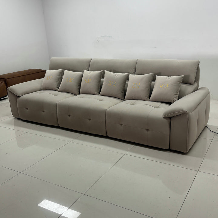 Modern beige sectional sofa with tufted cushions and embroidered throw pillows in a minimal room