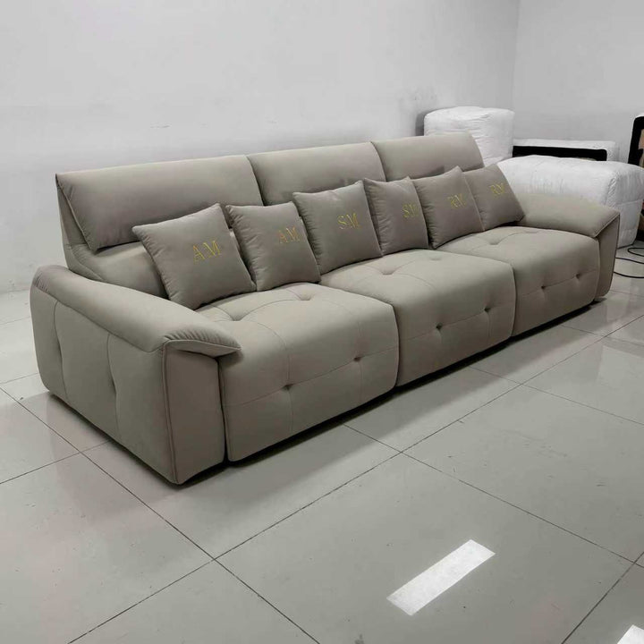 Modern beige sectional sofa with tufted seats and embroidered accent pillows in a minimalist room