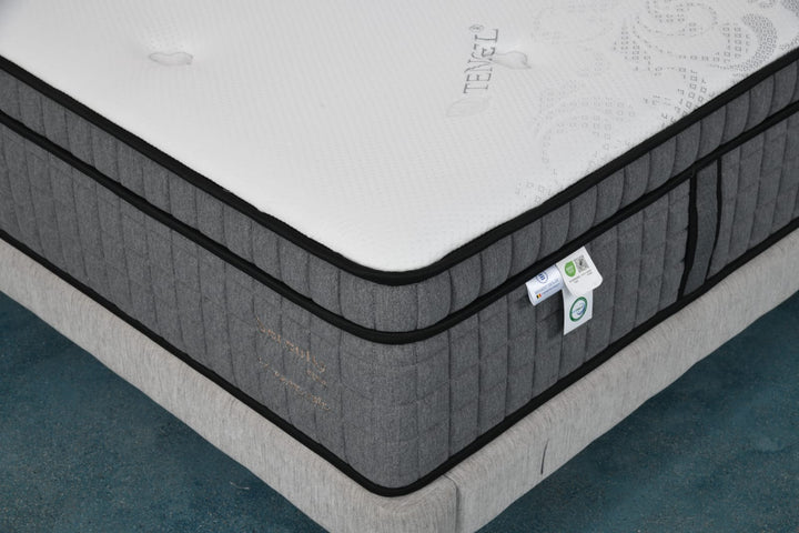 Close-up of a modern gray and white mattress on a bed frame, with Tencel branding.