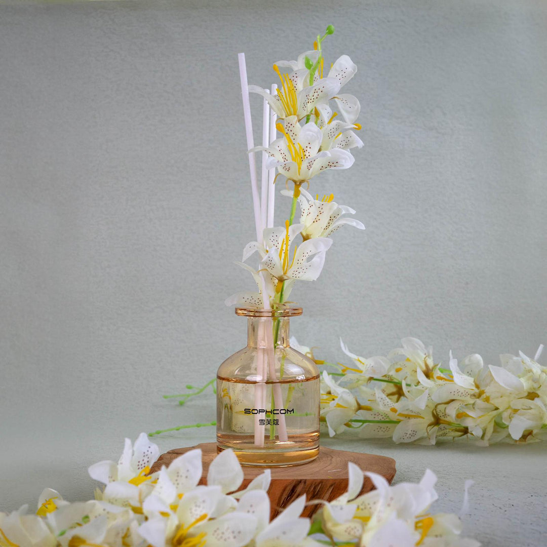 Glass diffuser bottle with white lily flowers and reed sticks, elegant home decor accent