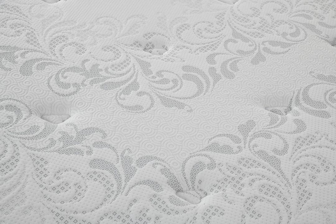 Close-up of a white mattress with textured floral pattern and tufted surface detail.