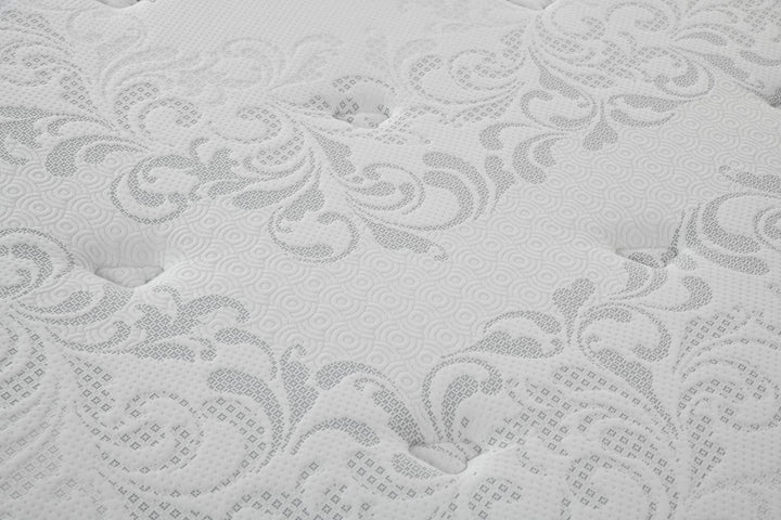 Close-up of a white mattress with textured floral pattern and tufted surface detail.