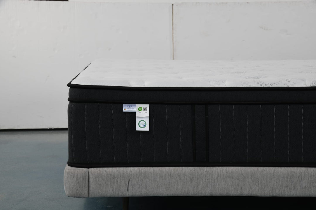 Modern mattress with black sides and white top on upholstered bed base