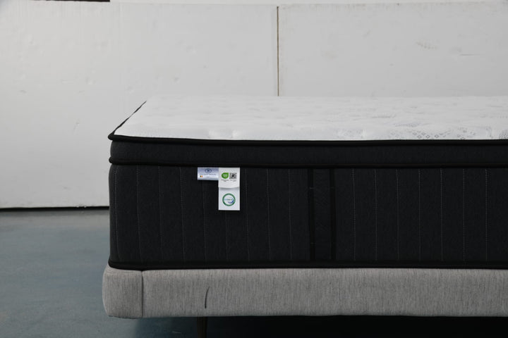 Modern mattress with black sides and white top on upholstered bed base