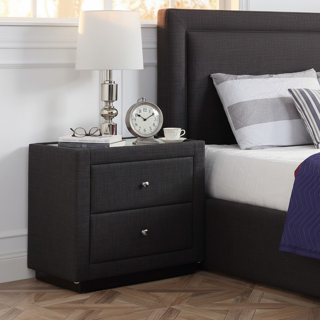 Modern dark gray upholstered nightstand with lamp, clock, and books in bedroom