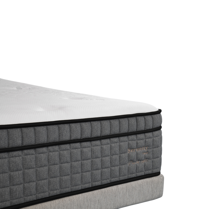 Close-up of a modern grey and white luxury mattress with quilted sides and embroidered details.