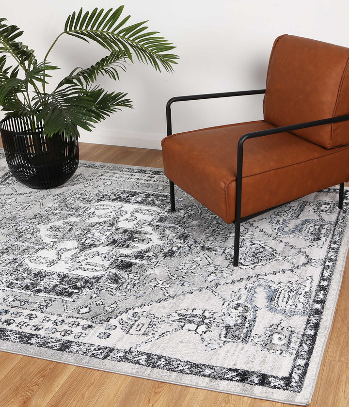 Modern brown armchair on patterned grey area rug with black planter and green plant