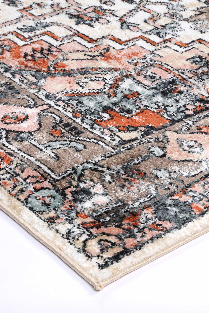 Close-up of a modern area rug with abstract geometric pattern in beige, orange, and gray tones.