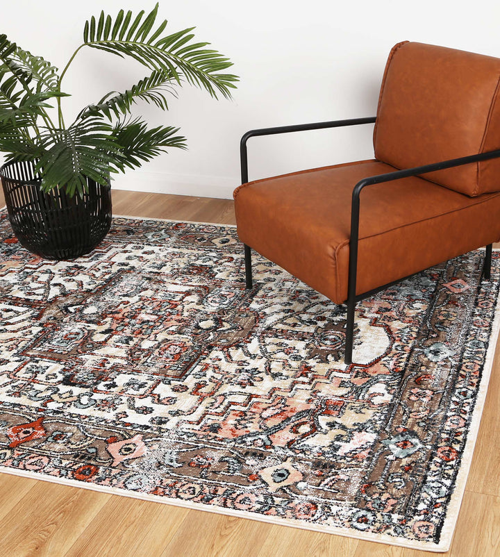 Modern living room with brown leather accent chair, patterned area rug, and potted plant