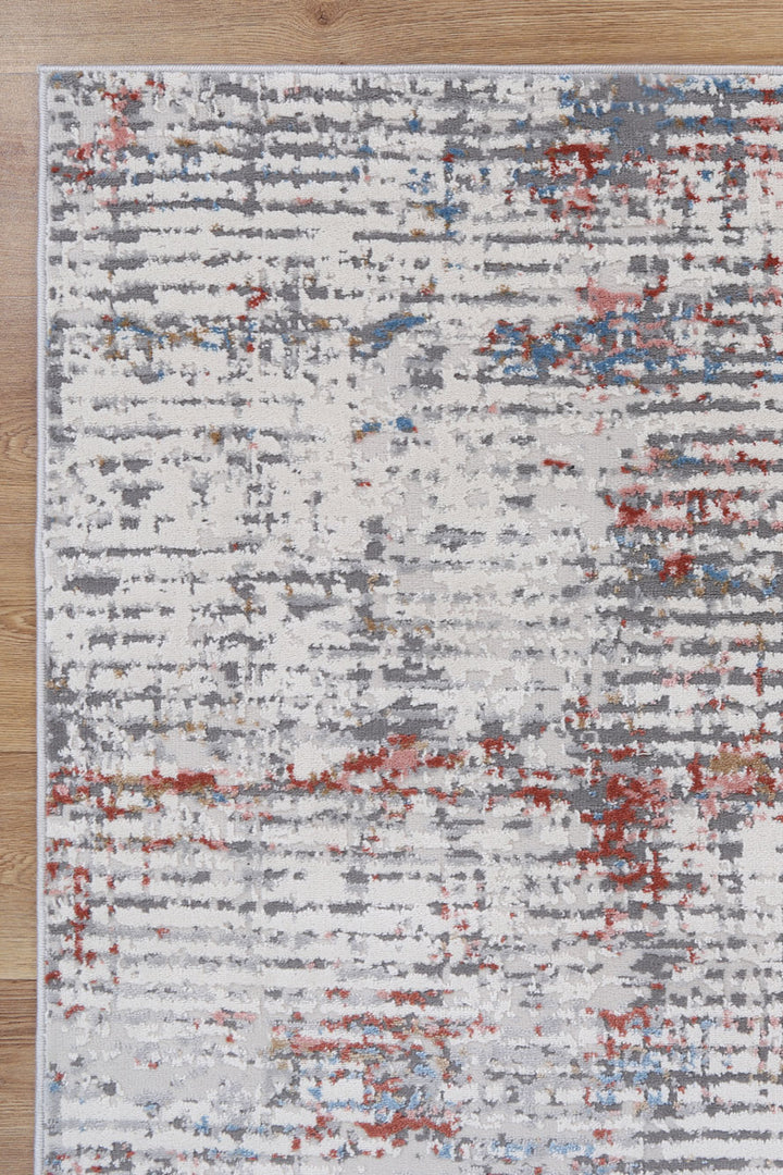 Modern abstract area rug with gray, red, and blue patterns on light wood floor