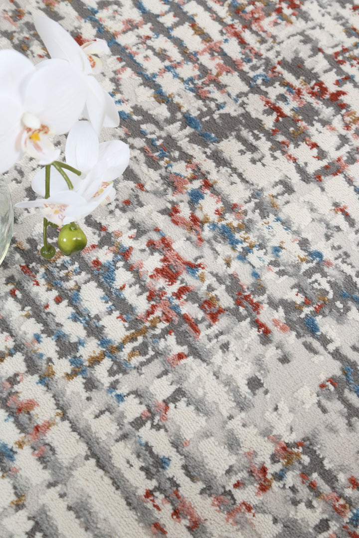 Abstract pattern area rug with gray, red, blue tones and white orchids in a glass vase