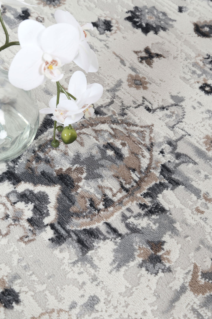 Modern area rug with gray, beige, and black patterns, glass vase with white orchids