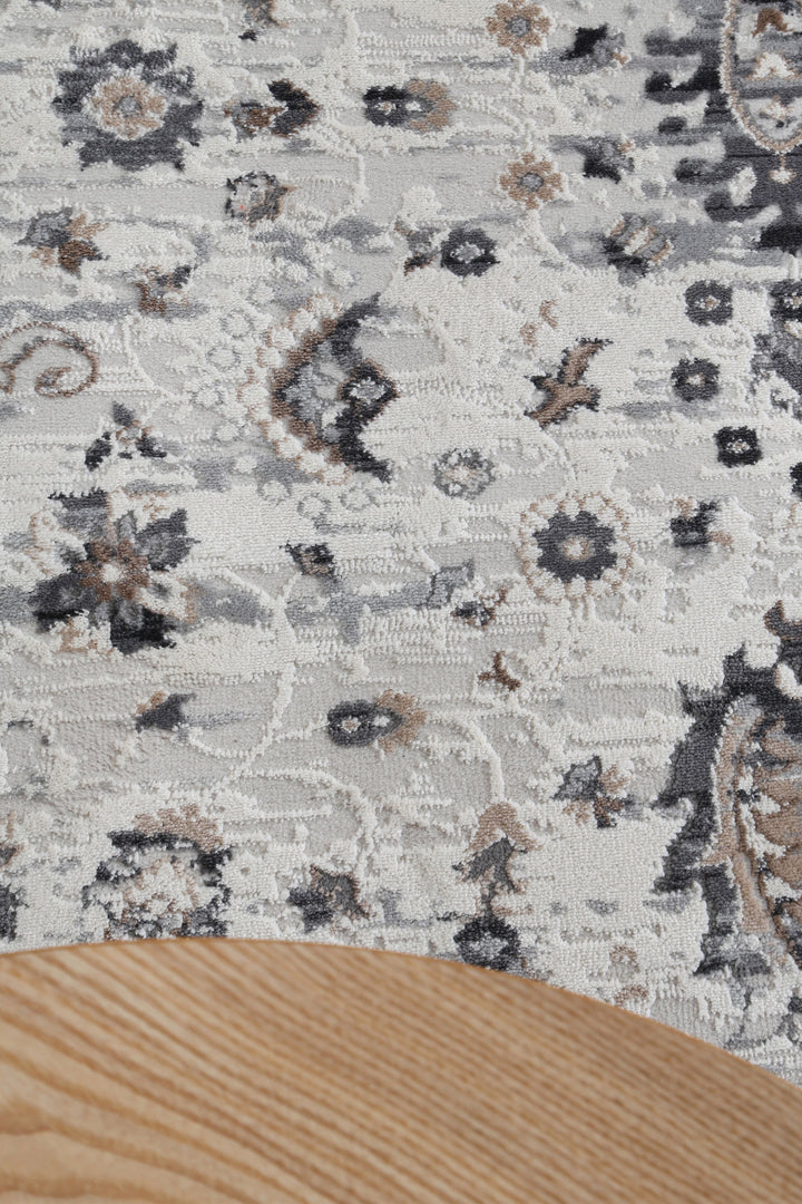 Close-up of grey patterned area rug with light wood table edge in home setting