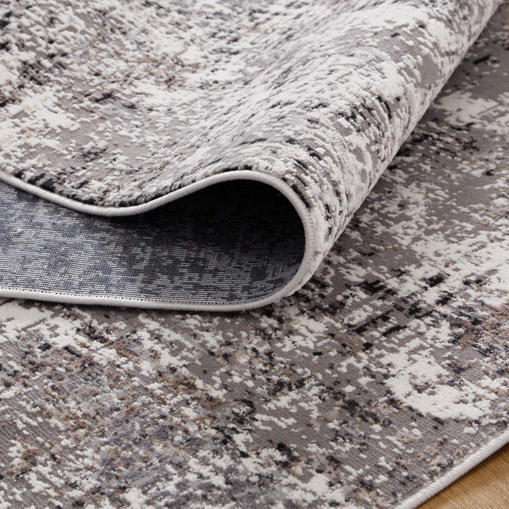 Modern abstract area rug with gray, beige, and white pattern on wood floor