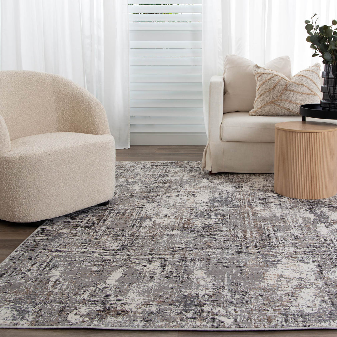 Modern living room with cream accent chair, beige sofa, abstract area rug, and round wood side table