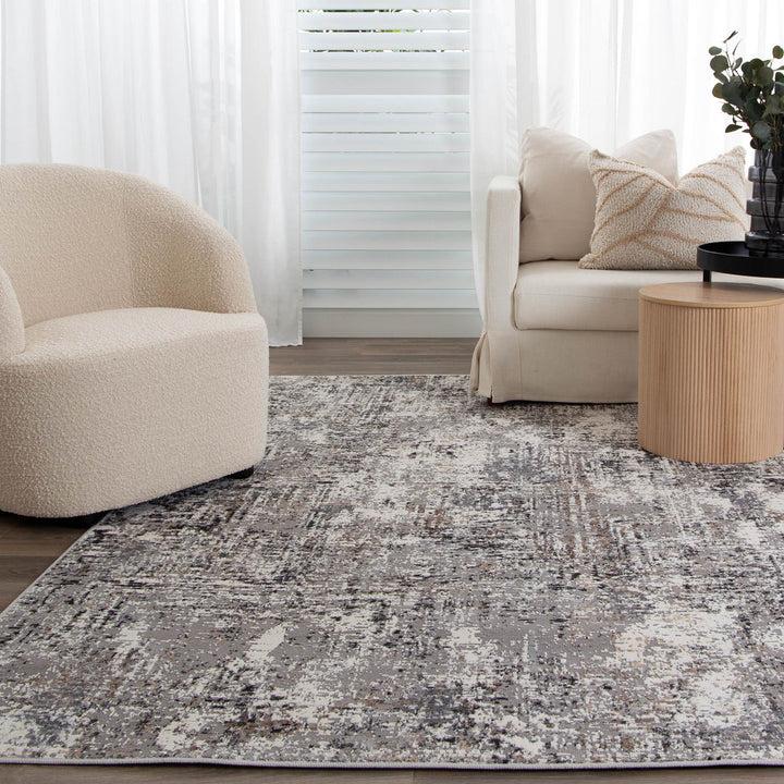 Modern living room with cream accent chair, beige sofa, abstract area rug, and round wood side table