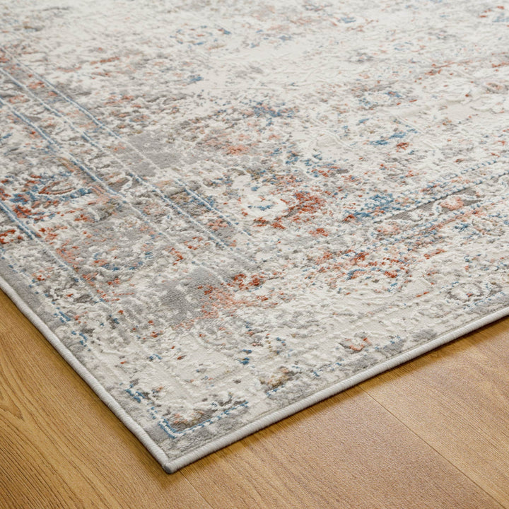 Modern distressed area rug with grey, blue, and rust accents on hardwood floor