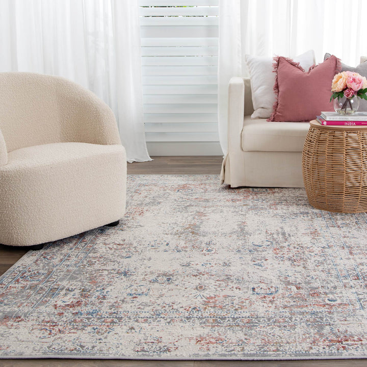 Modern living room with a beige accent chair, cream sofa, woven side table, and distressed area rug