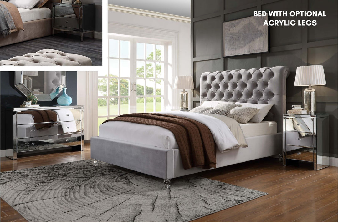Grey tufted queen bed with acrylic legs, modern mirrored nightstands, and a stylish bedroom setting